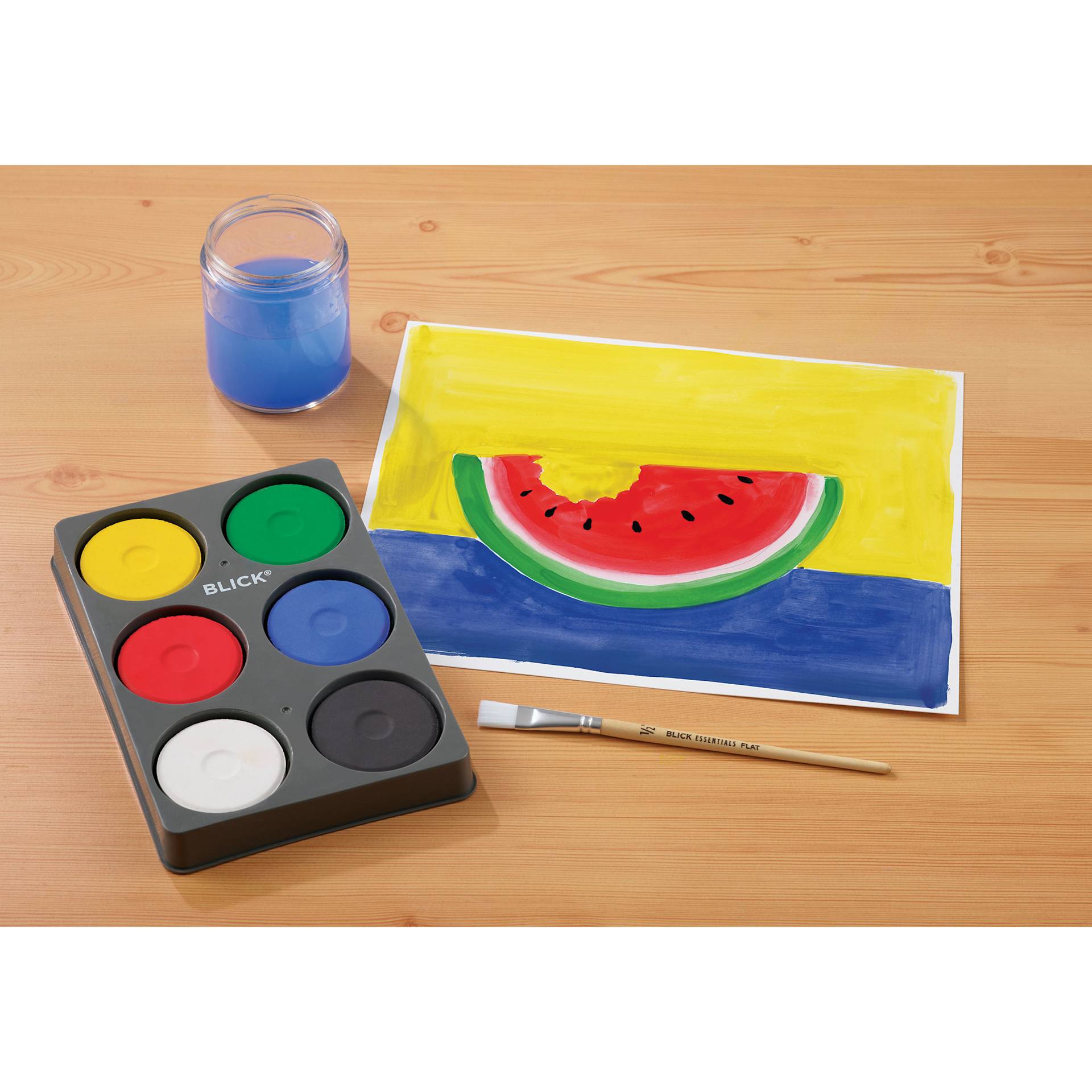 Blick Essentials Tempera Cakes Set of 6 Primary Colors in a Tray with brushes, a cup of water, and a painting of a watermelon.