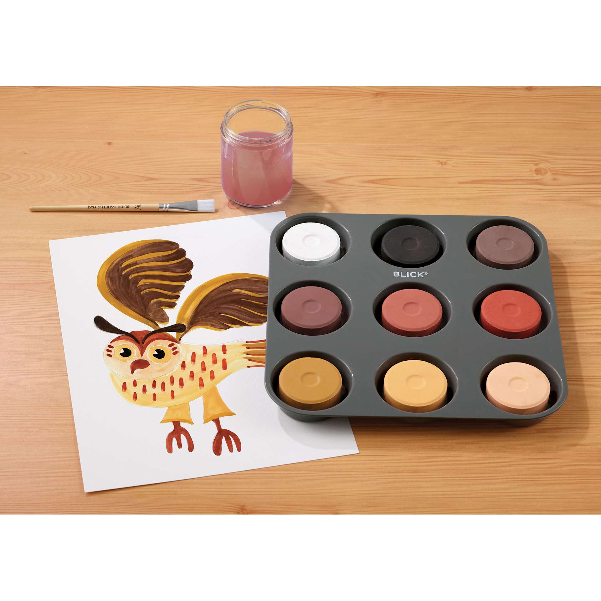 Blick Essentials Tempera Cakes Set of 9 Portrait Colors with a Tray, brush, cup of water, and a painting of an owl. 