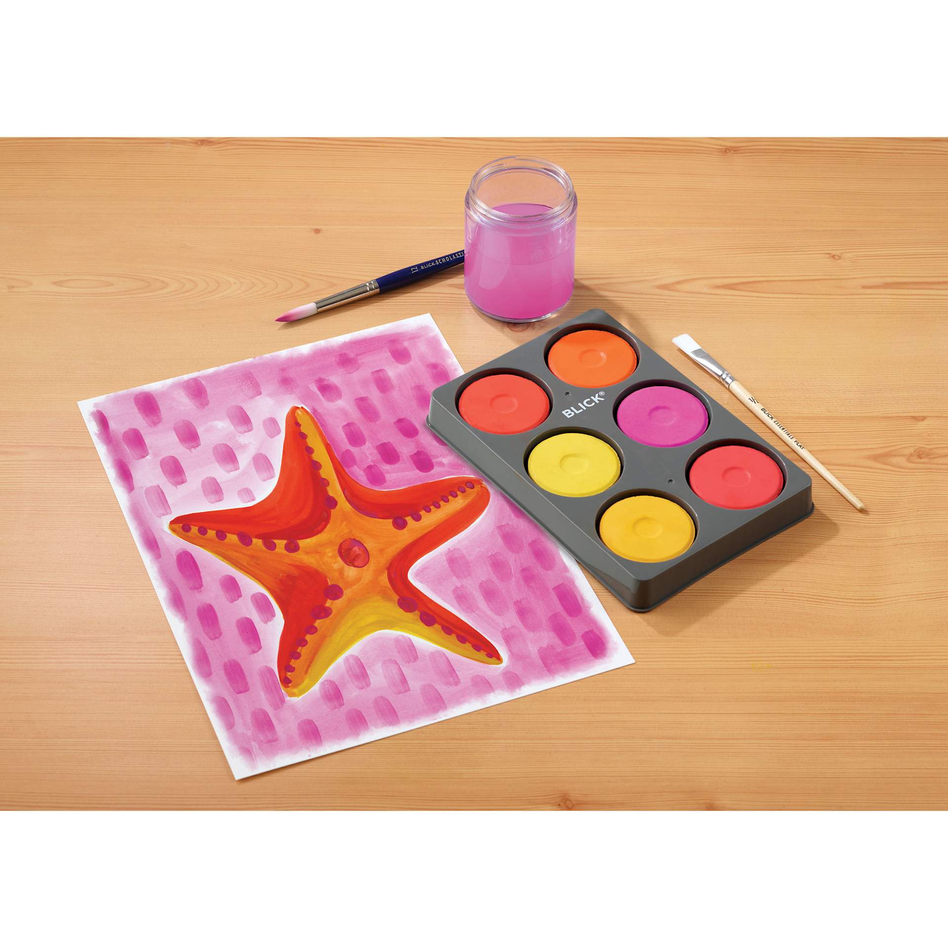 Blick Essentials Tempera Cakes Set of 6 Warm Colors with a Tray, brushes, water cup, and a painting of a star fish.