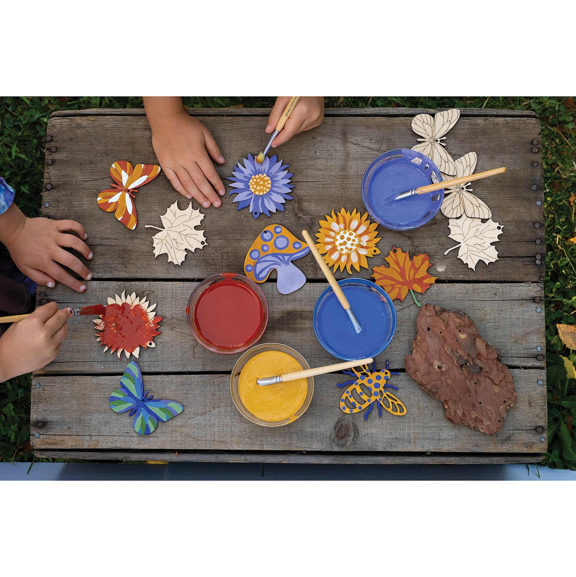 Hands using mixed Natural Earth Paint Tempera Paint to decorate wooden shapes.