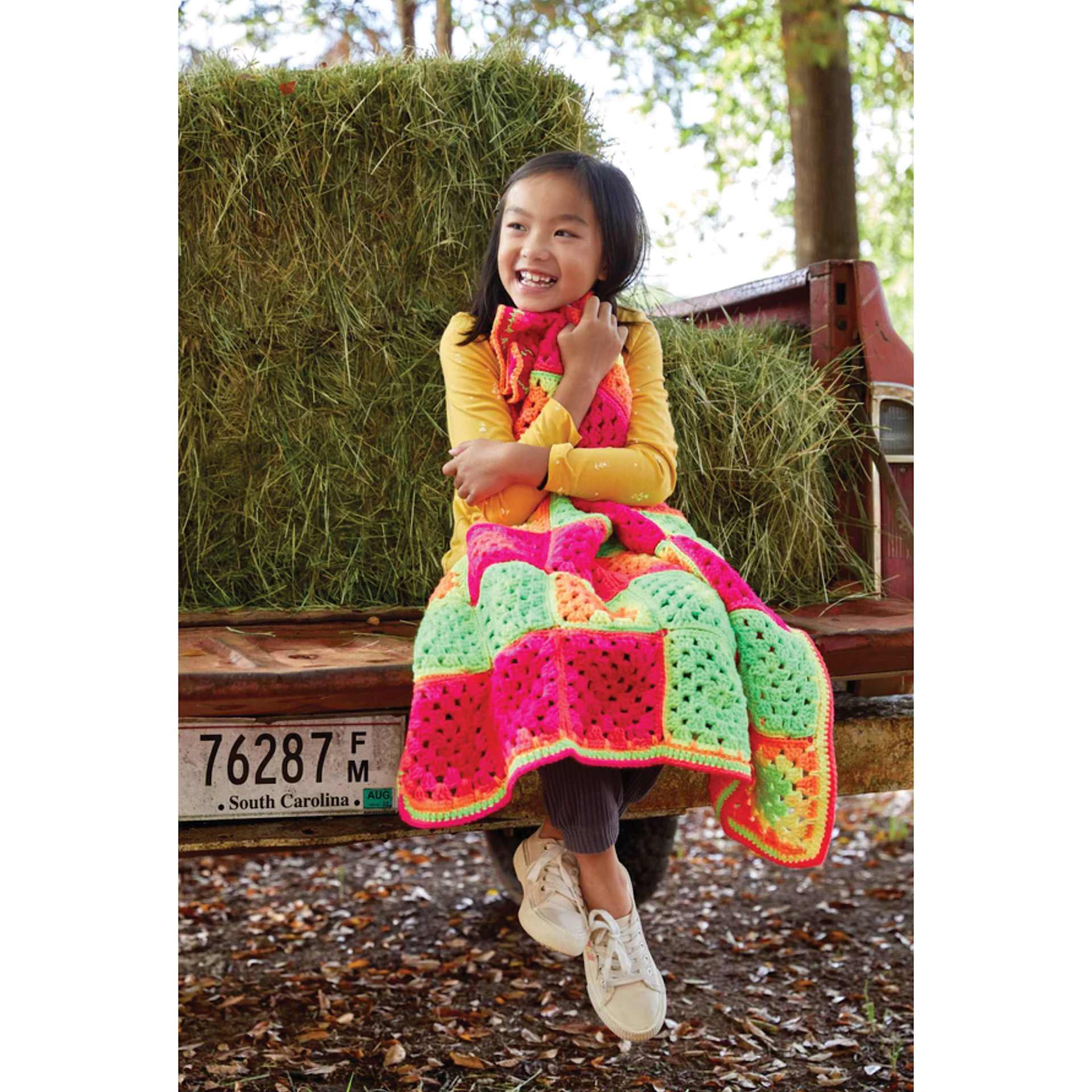 Premier Yarn Sweet Roll Vivid, child wearing finished blanket made of yarn