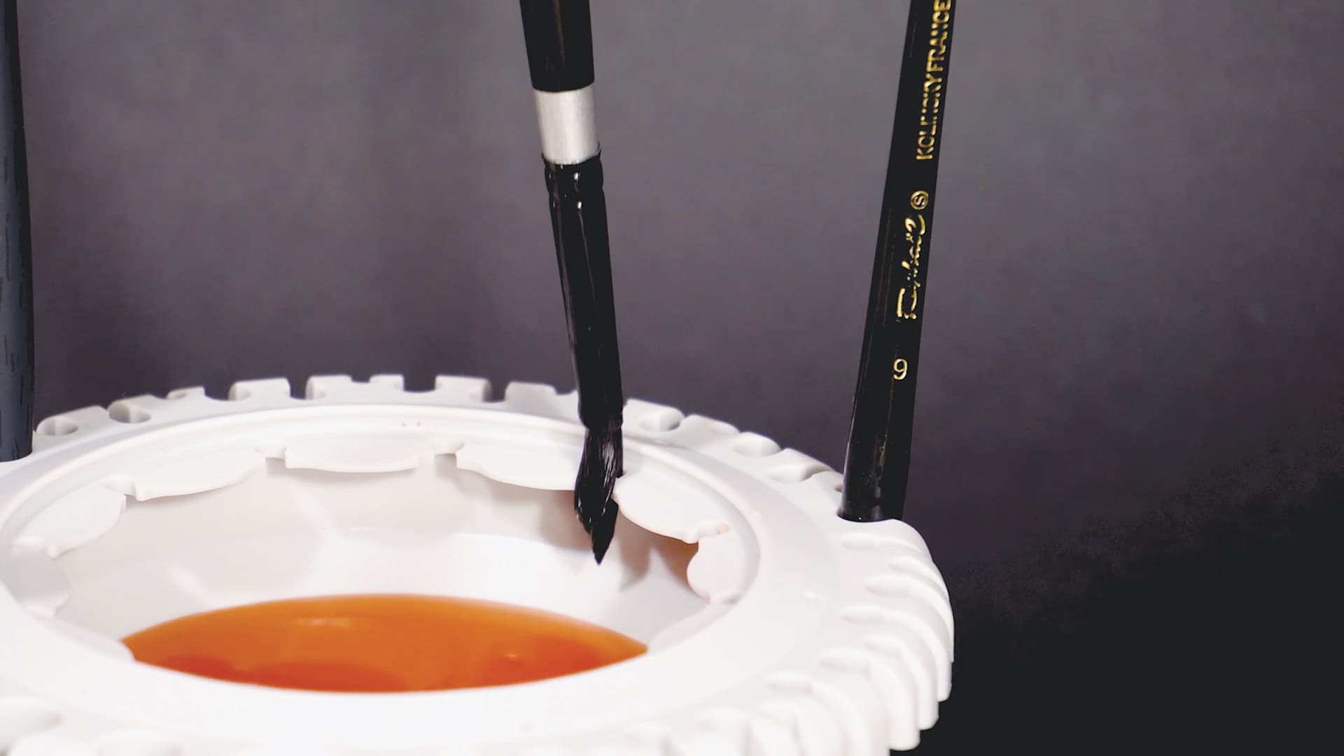 Paint Puck CollapsiBowl Portable Brush Cleaner, holding brush after being cleaned