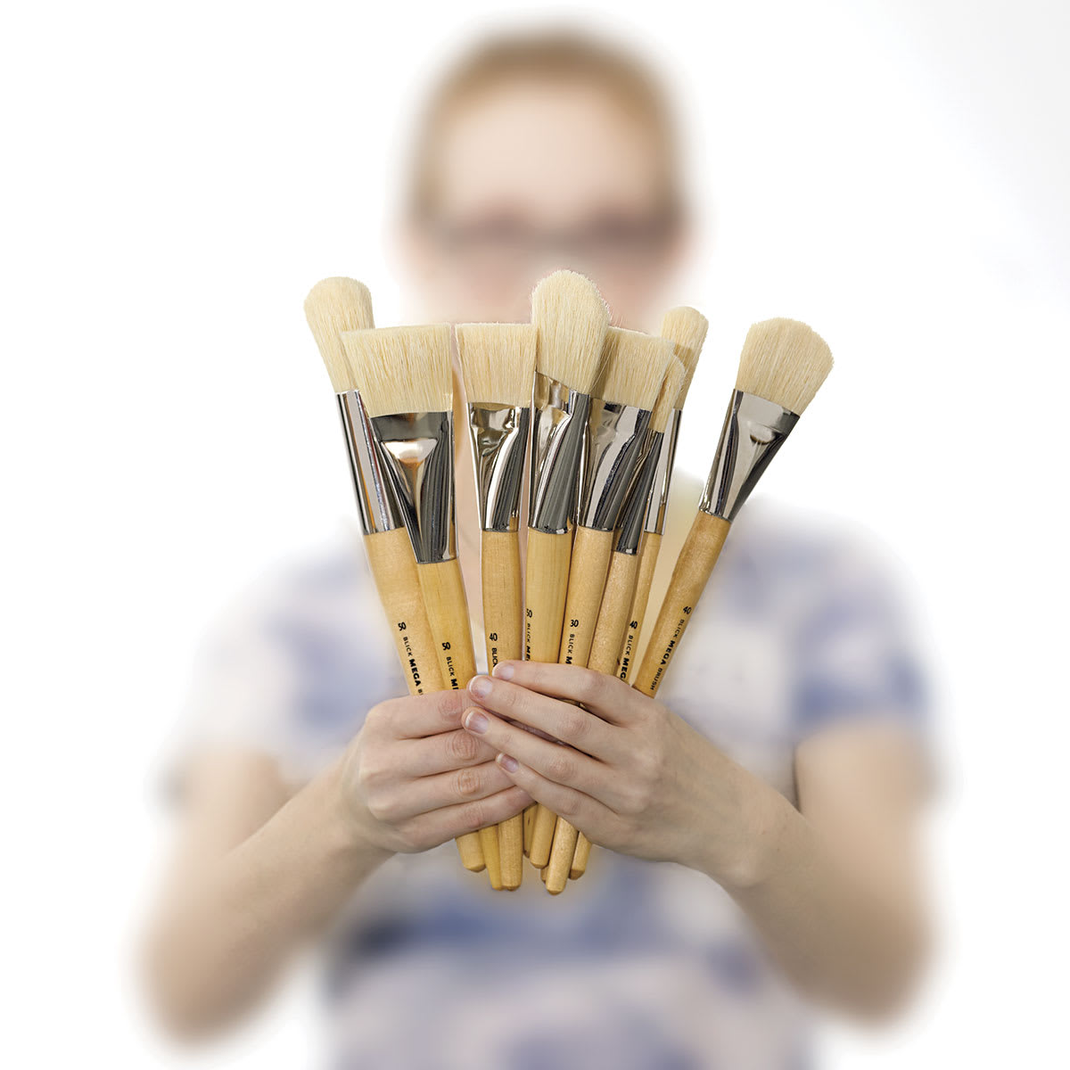 Blick Mega Natural Bristle Brushes - Model holding a fan of several brushes in front of her face

