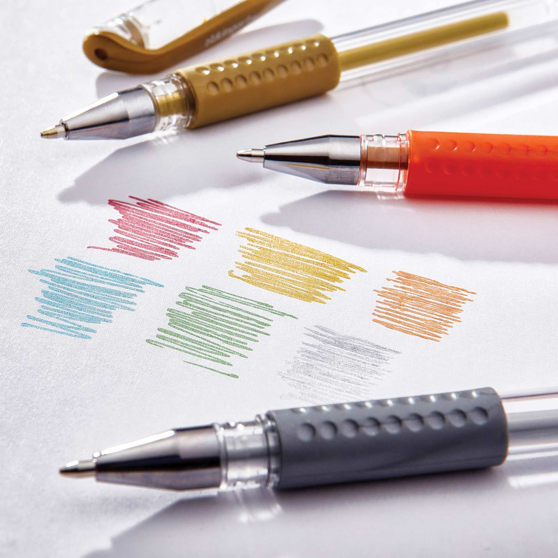 Kingart Studio Gel Pens - Set of 20, Metallic Colors, three pens laid on paper with pen swatches