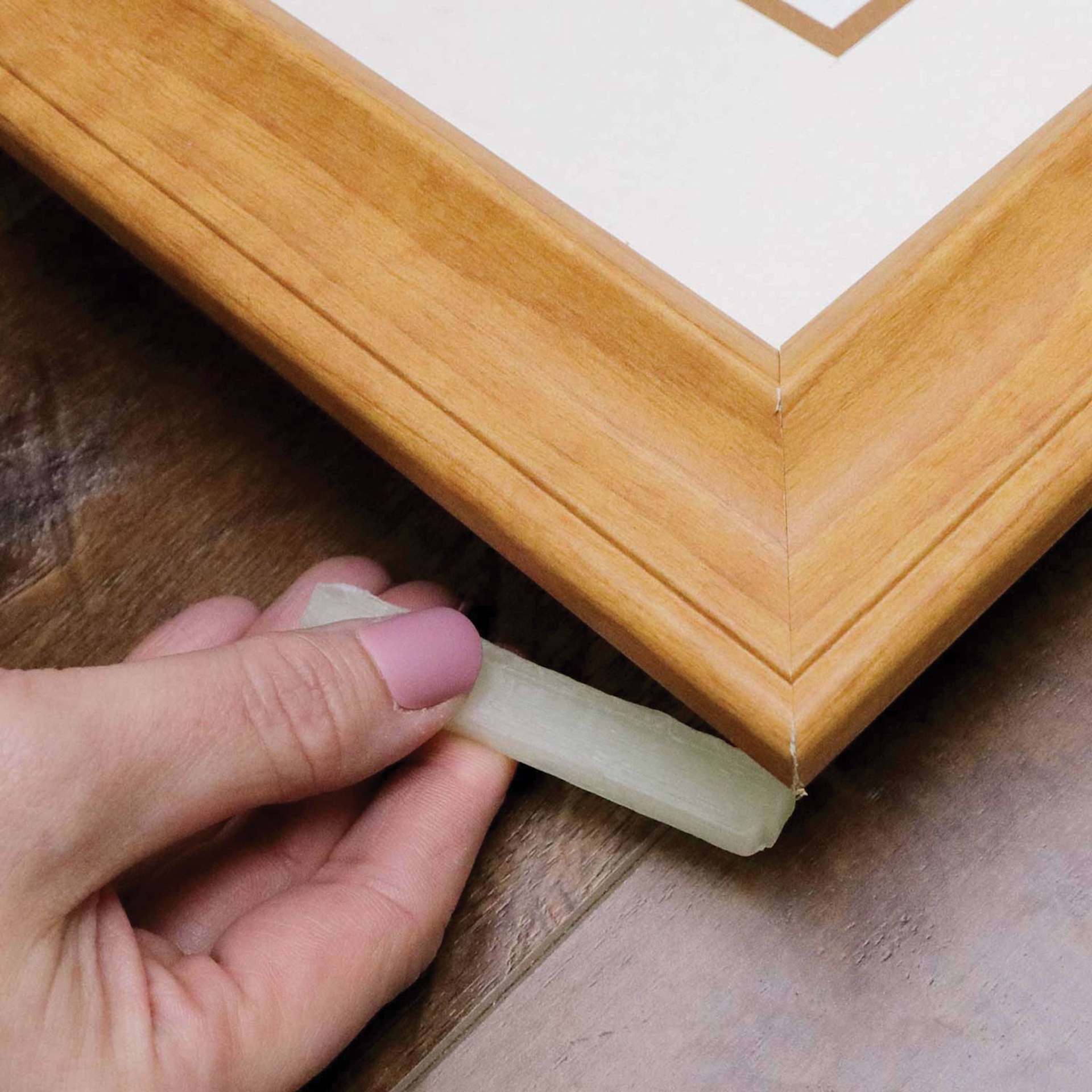 StikkiWorks StikkiWax Adhesive - Pkg of 12, hand placing stick behind frame