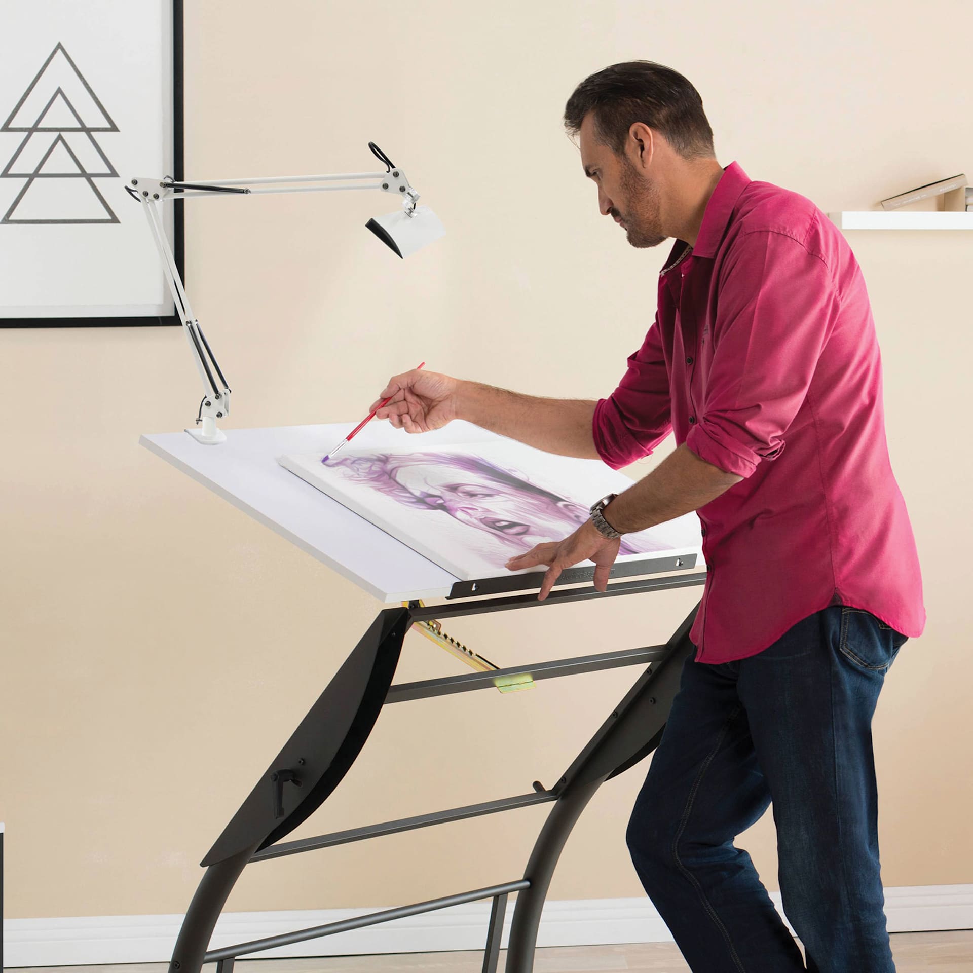 Studio Designs Ascend LED Swing Arm Lamp, clamped to table being used by an adult while drawing