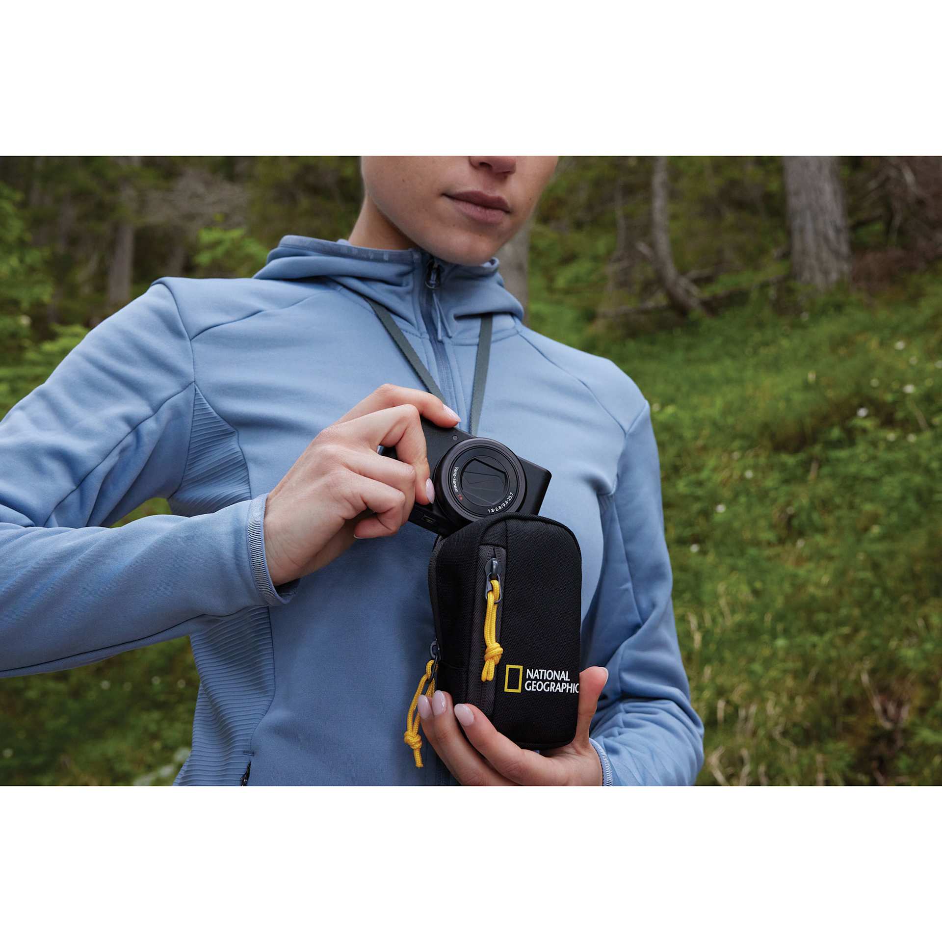 National Geographic Camera Pouch, in hand removing camera (not included) from the top of the pouch