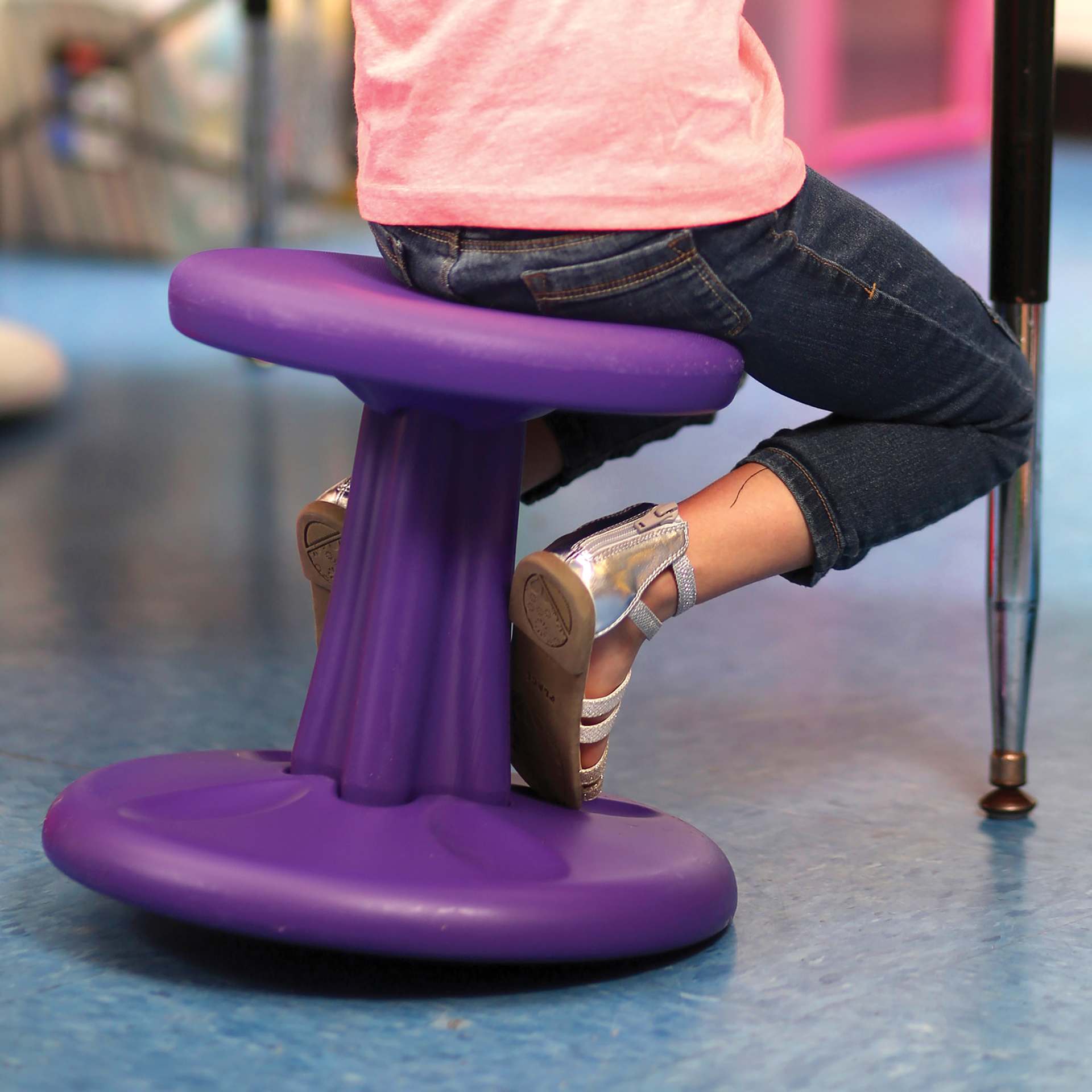 Child sitting on a purple Kore Design Kids Wobble Stool.