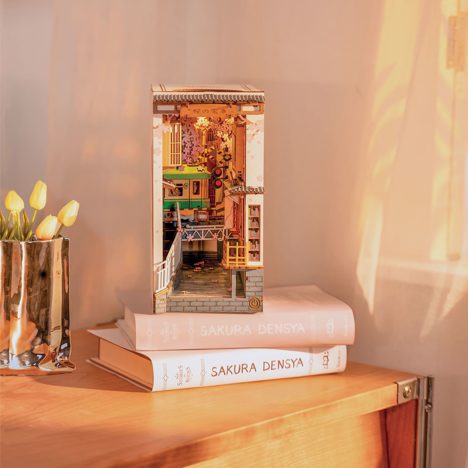 Rolife Sakura Densya DIY Book Nook Kit, constructed kit sitting on top of books