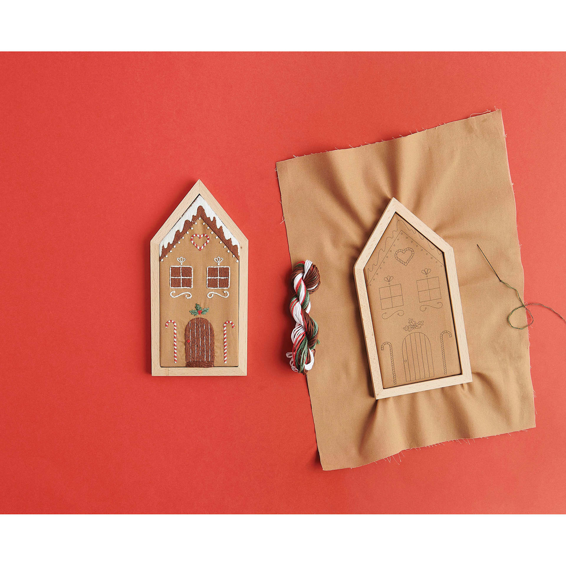 Rico Design Embroidery House Kit - Gingerbread House finished product next to in-process project