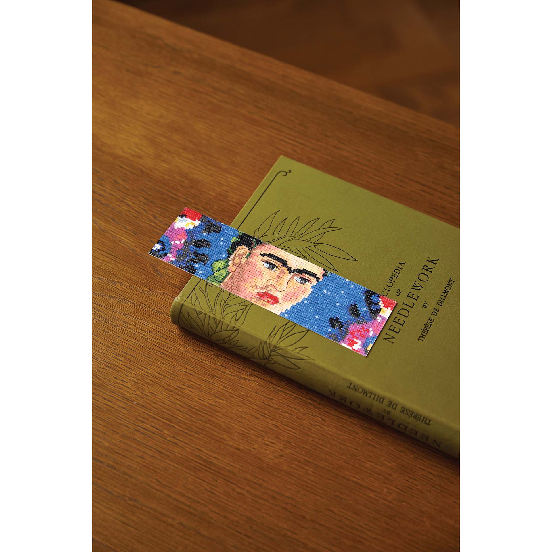 DMC The Masters Collection Cross Stitch Bookmark Kit - "The Frame" by Frida Kahlo ontop of book