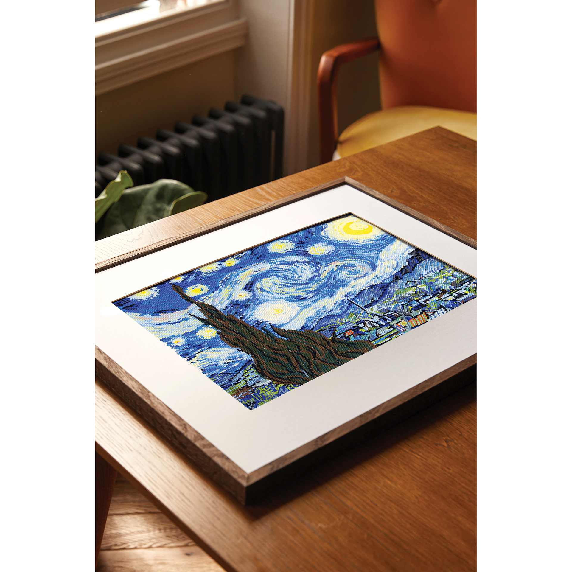 DMC The Masters Collection Cross Stitch Kit - “The Starry Night” by Vincent van Gogh framed laying on table