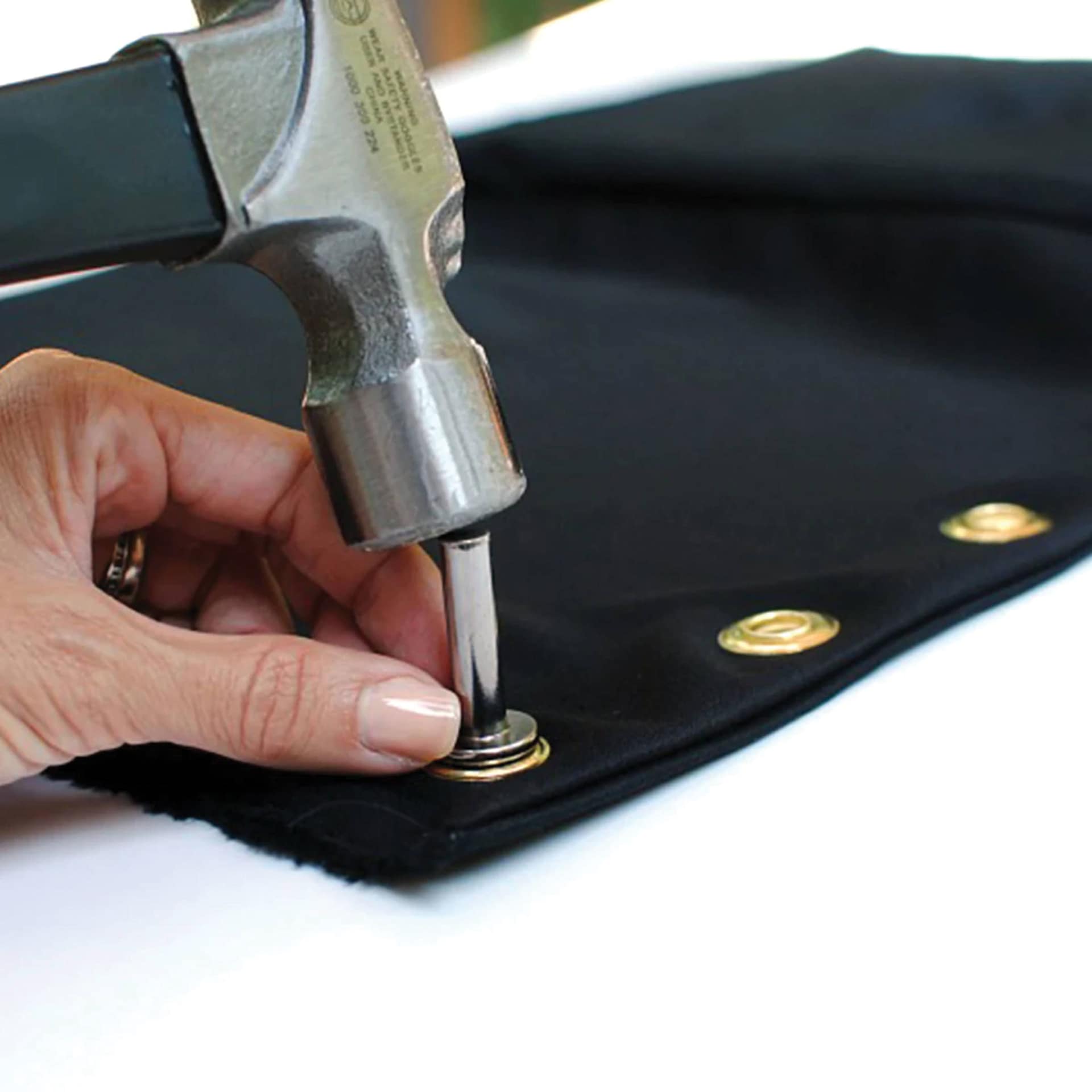 Dritz Eyelets - Brass, being hammered into fabric