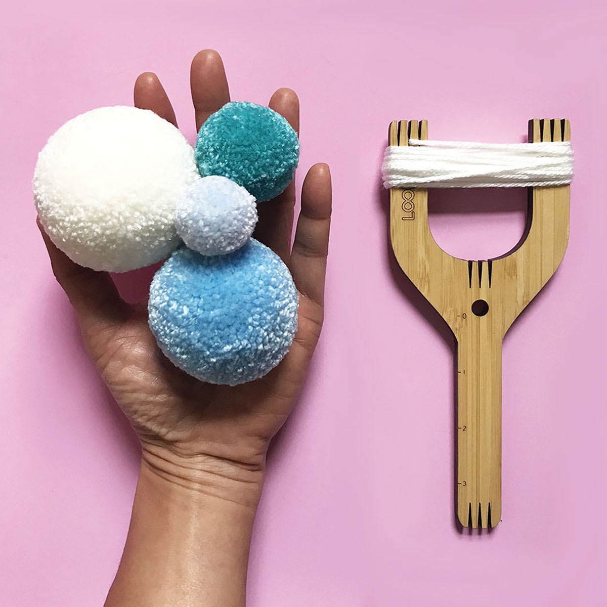 Loome Fiber Craft Tools - Hand holding pompoms with Slingshot Loome Tool