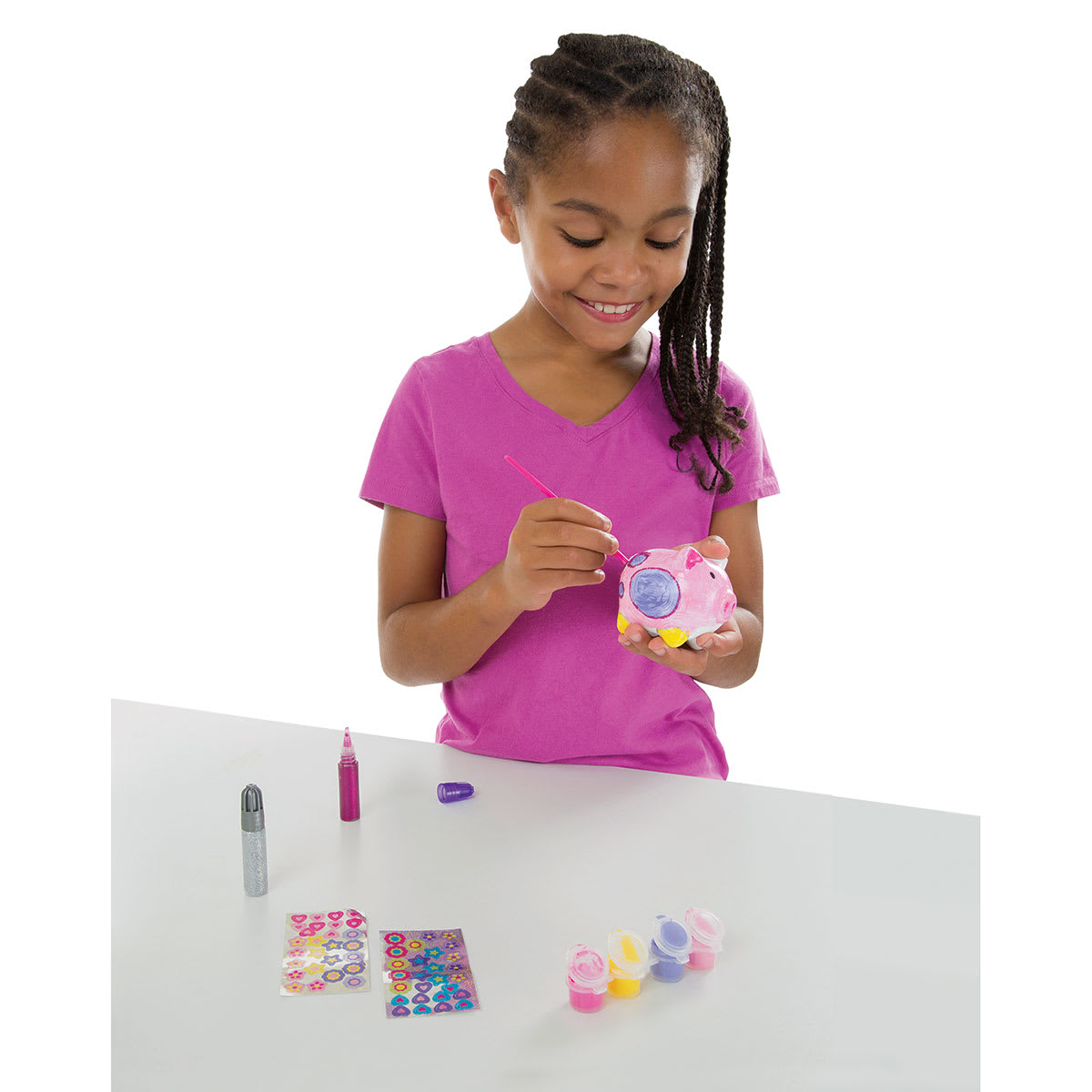 Created by Me Banks - Child at table with paints, holding and painting Piggy Bank