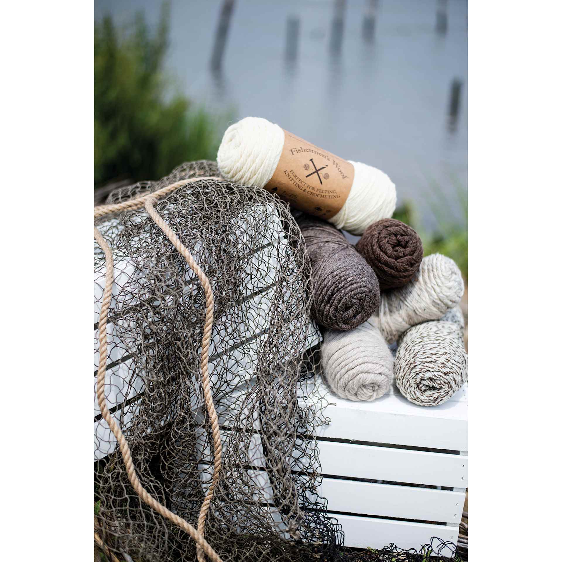 Lion Brand Fishermen's Wool Yarn collection of skeins on crate next to fishing net and lake