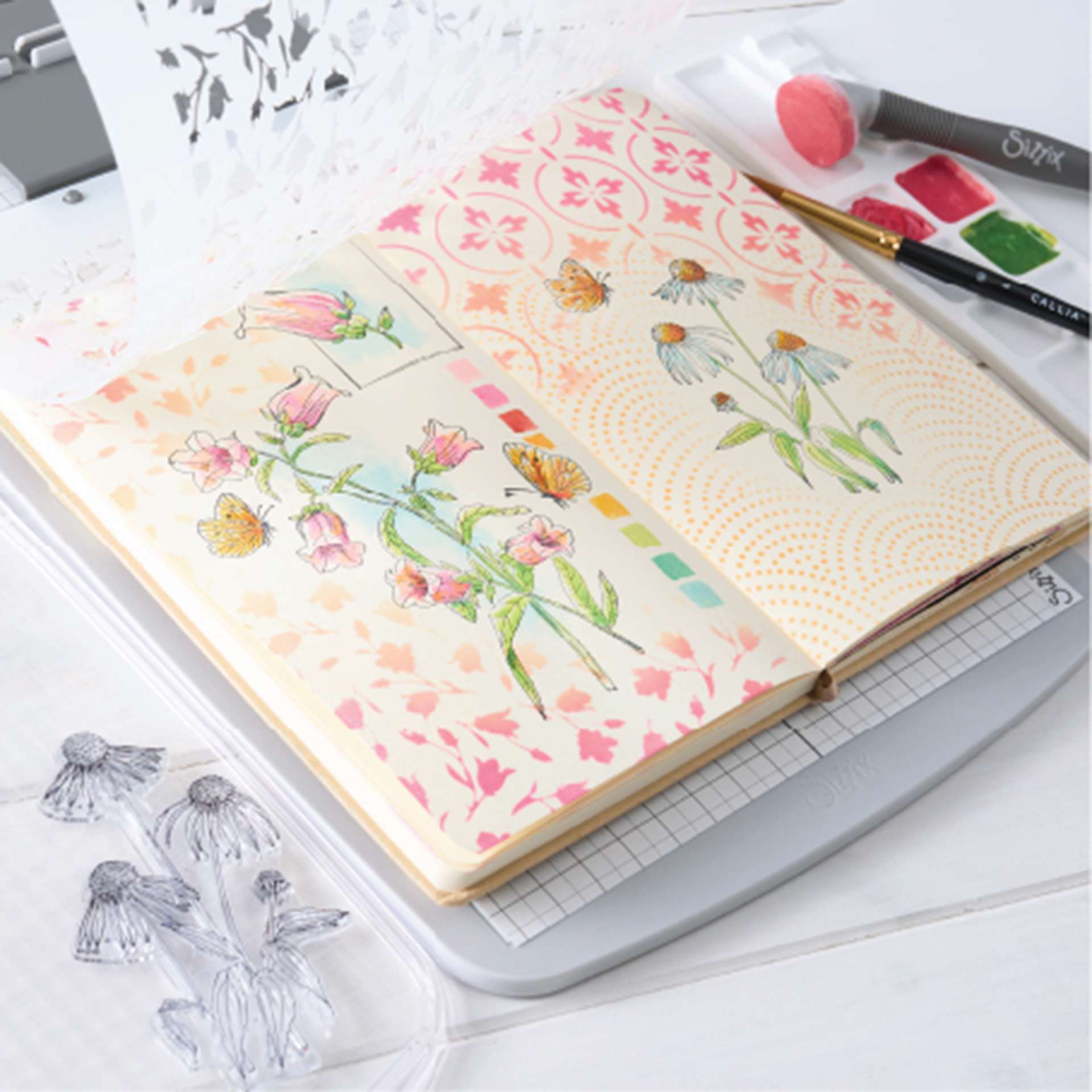 Sizzix Studio Registration Press Tool Starter Kit showing completed floral design project in notebook