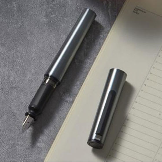 Sailor TUZU Adjust Fountain Pen - Gunmetal, Medium, pen and cap resting on tabletop with stationary.