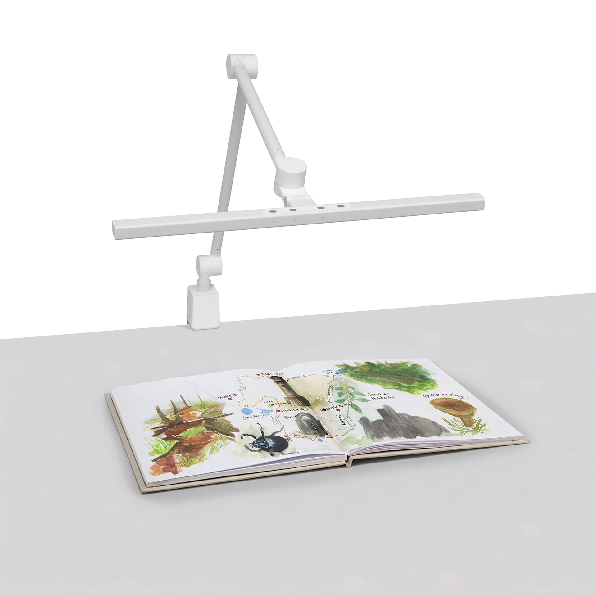 Artograph T-Bar Lamp with Table Clamp - White, on desk with artwork