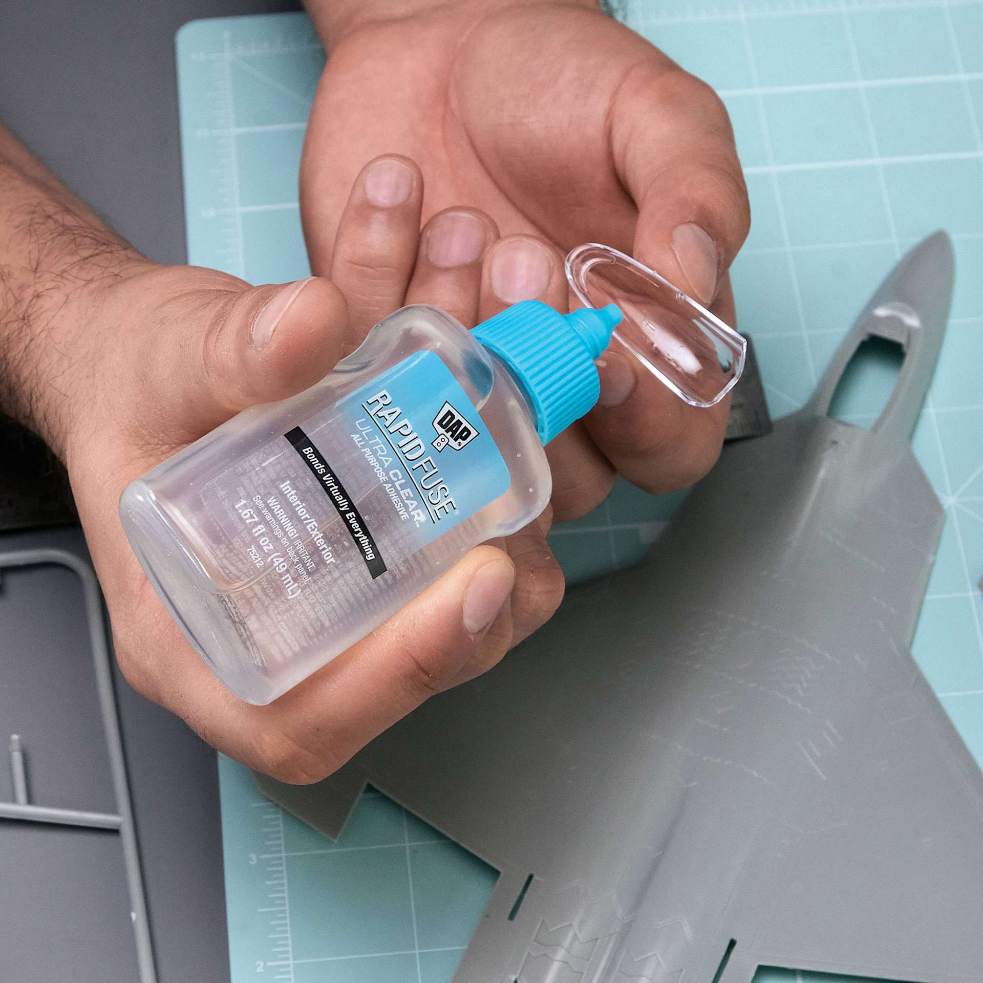 DAP RapidFuse Ultra Clear All Purpose Adhesive - 1.67 oz Bottle being applied to airplane model window