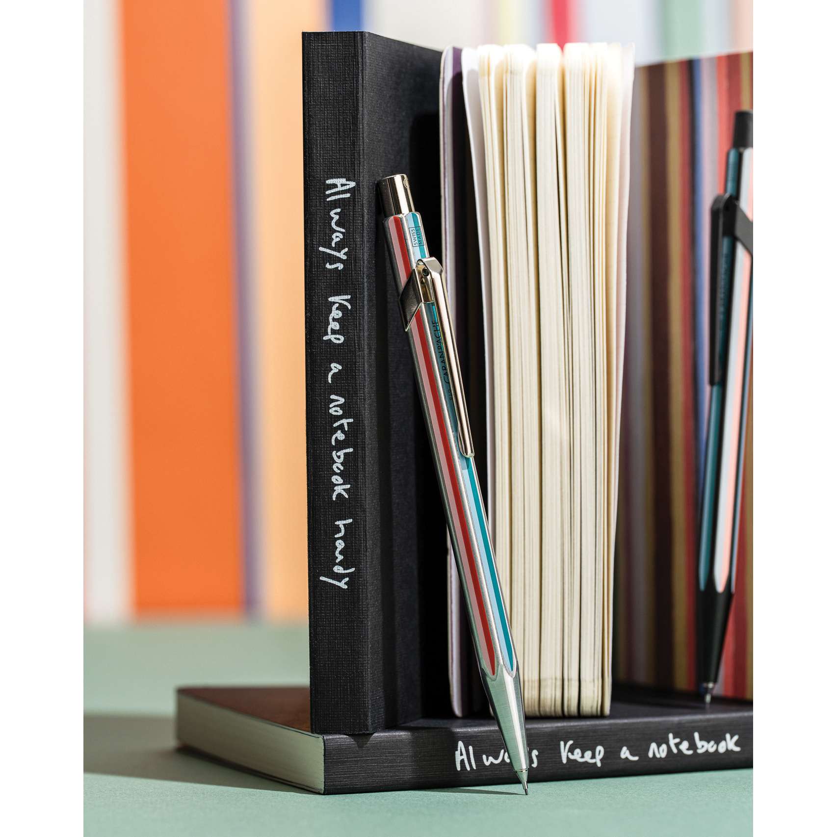 Caran d'Ache Paul Smith Special Edition 849 Mechanical Pencil - Raw Silver, 0.5 mm, propped up against a notebook