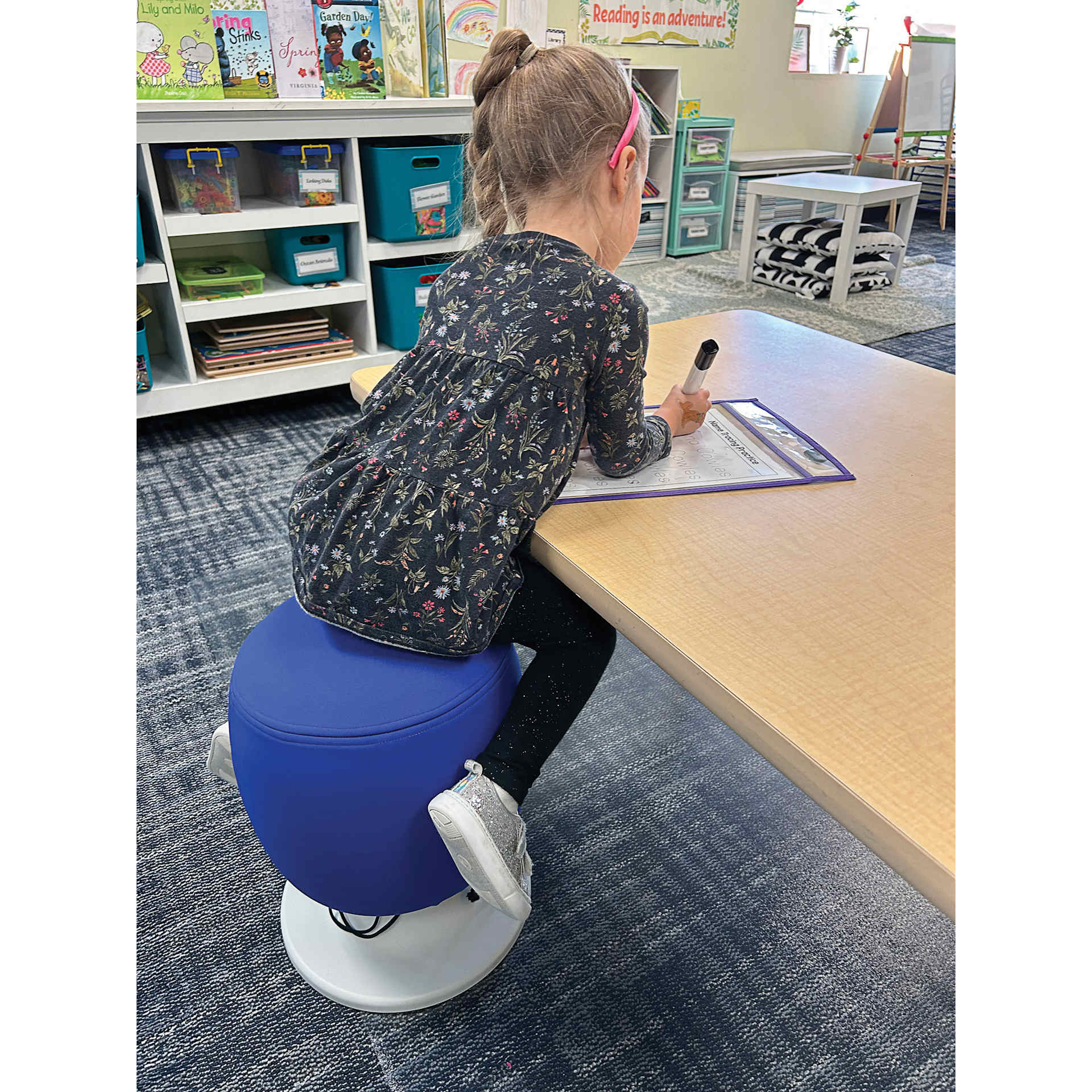 Child sitting on a blue Kore Design Kid’s Adjustable Pivot Stool.