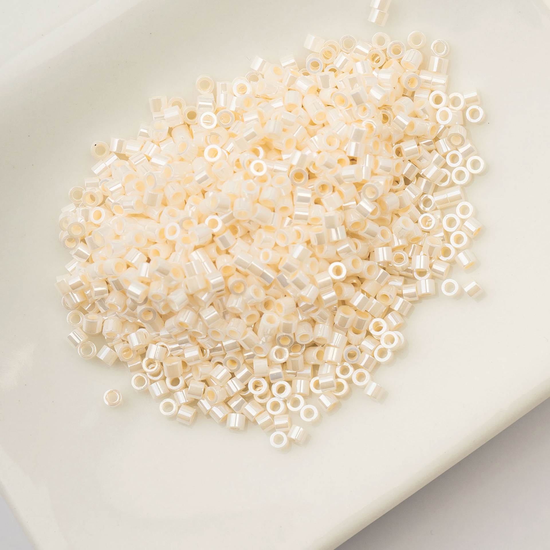 John Bead Cylin 11/0 Ceylon Cylindrical Seed Beads - Opaque White Bisque, 25g sitting in dish