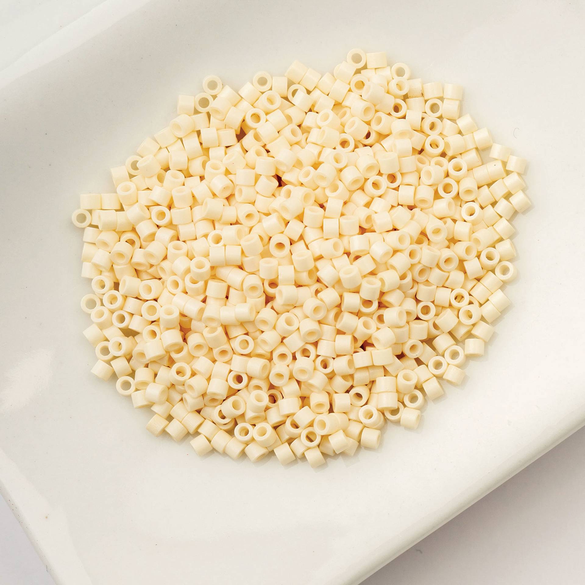 John Bead Cylin 11/0 Cylindrical Seed Beads - Dark Cream sitting in dish