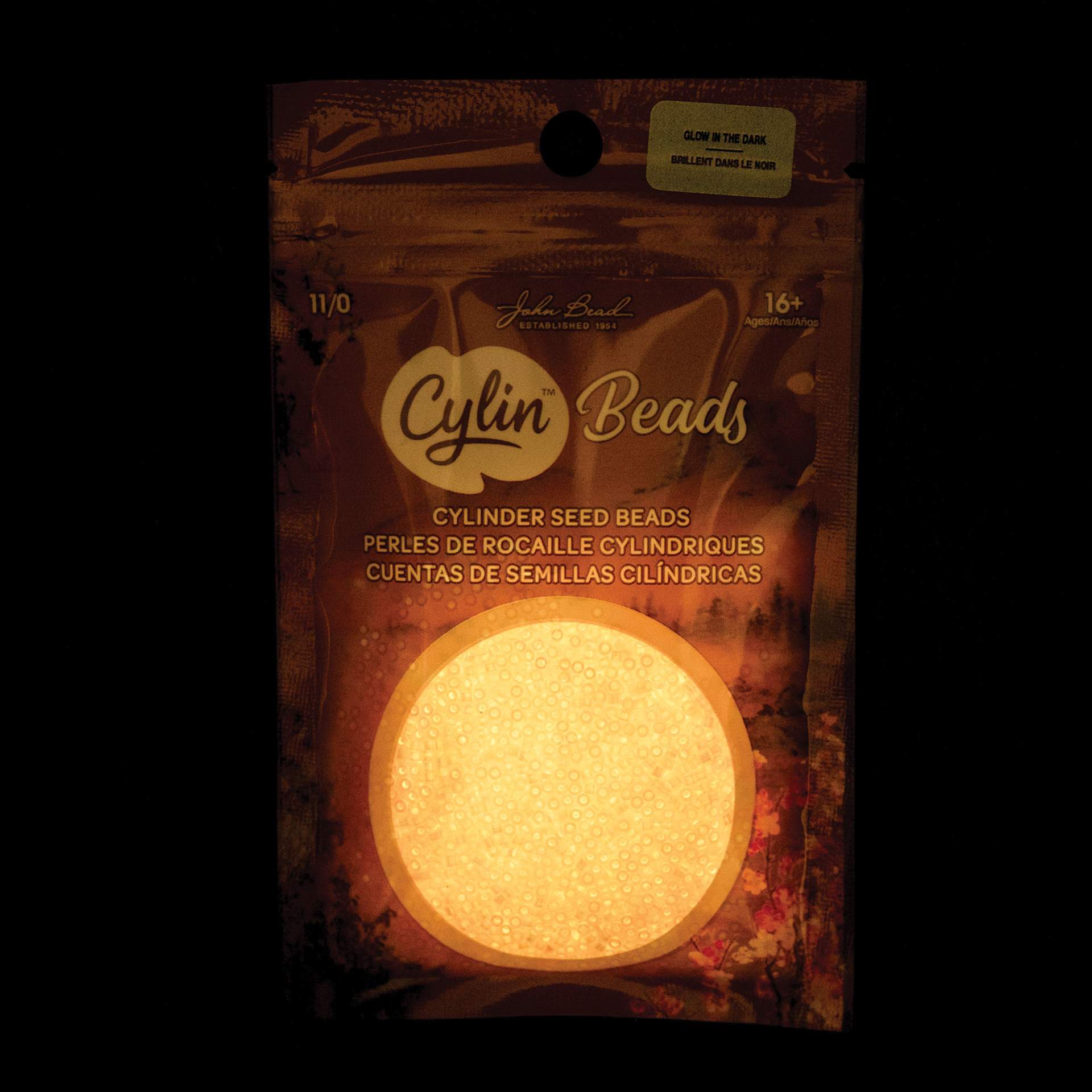John Bead Cylin 11/0 Glow in the Dark Cylindrical Seed Beads - Coral AB, 25g front of packaging to show glow effect