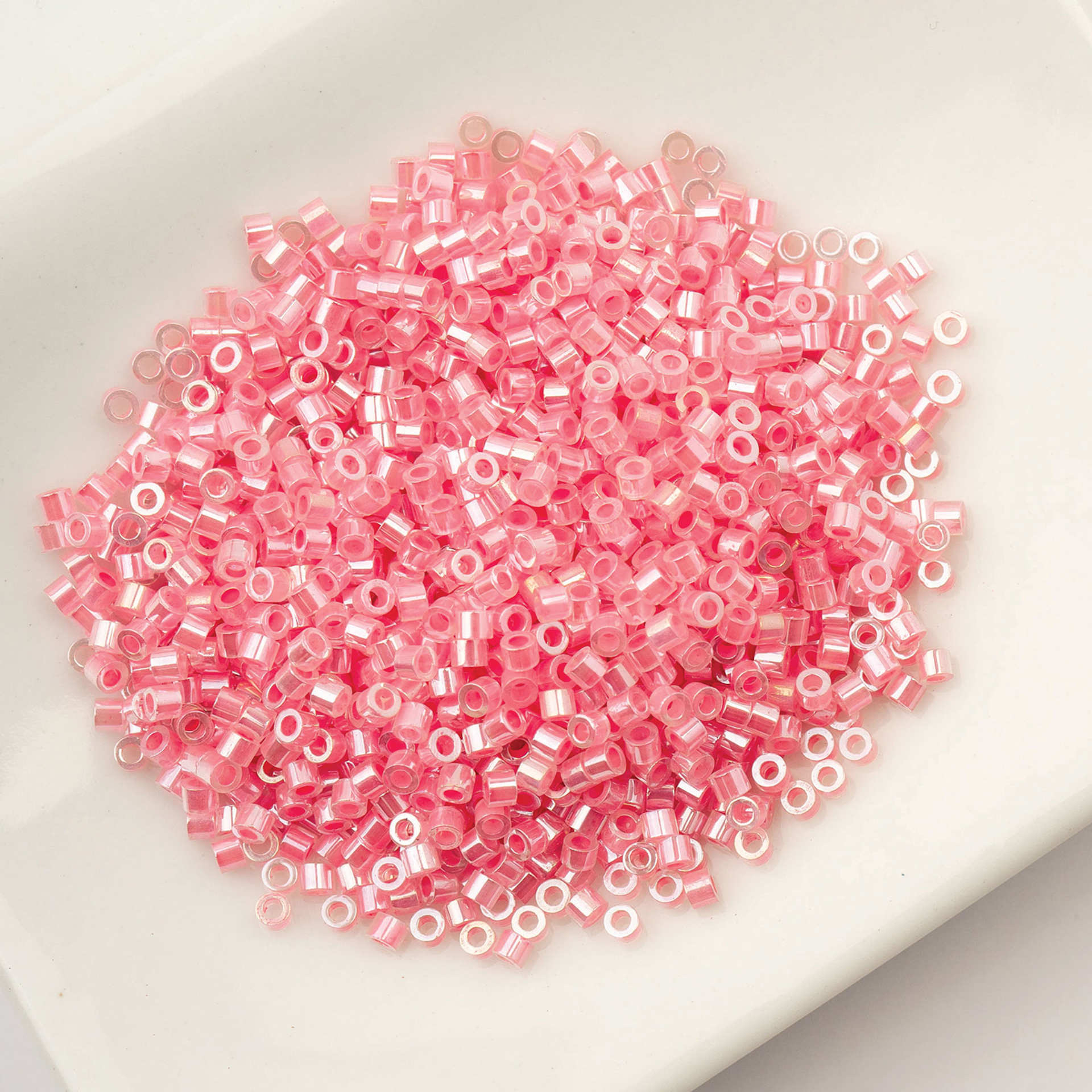 John Bead Cylin 11/0 Ceylon Cylindrical Seed Beads - Crystal Rose Lined, 25g sitting in dish