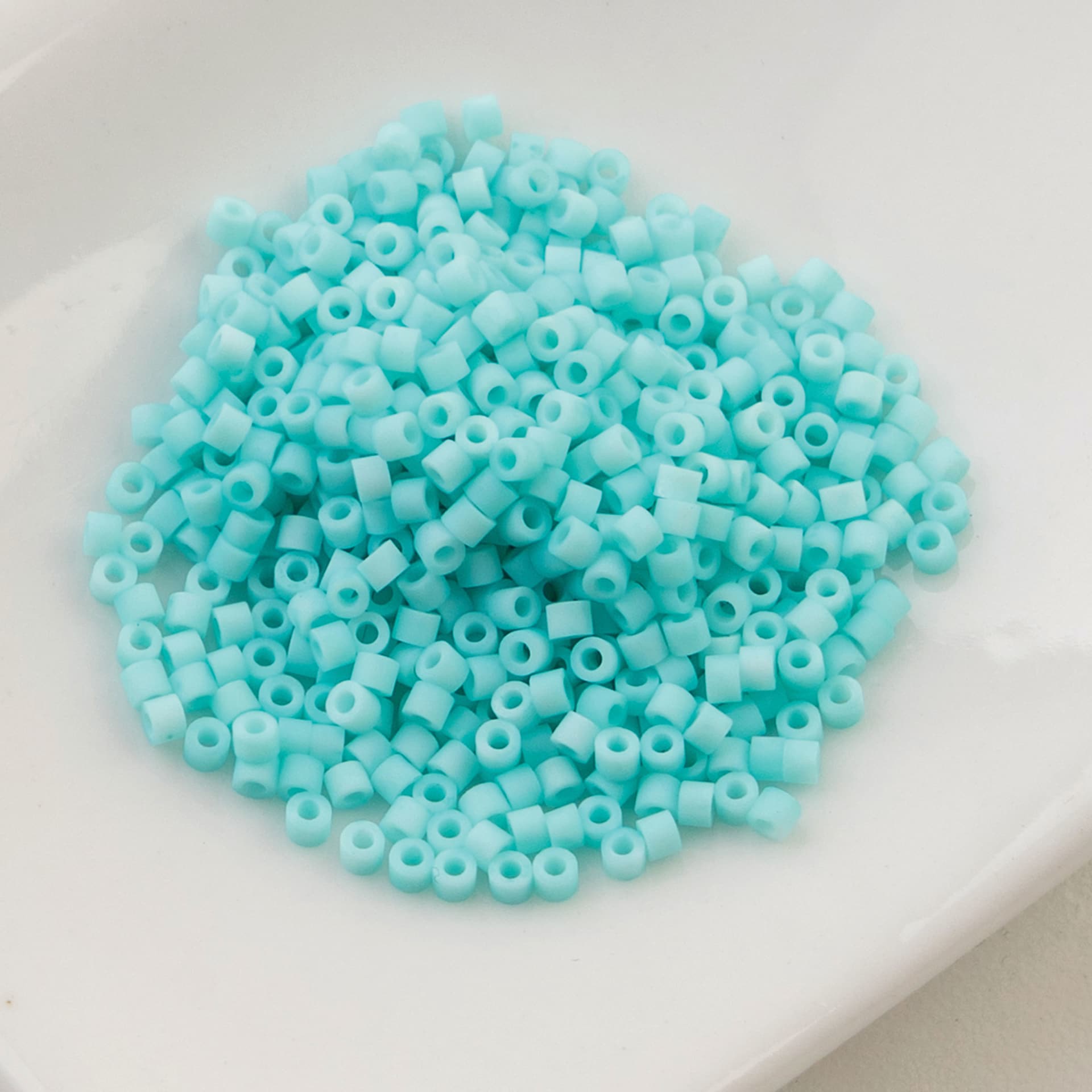 John Bead Cylin 11/0 Matte Macaron Cylindrical Seed Beads - Green Turquoise sitting in dish
