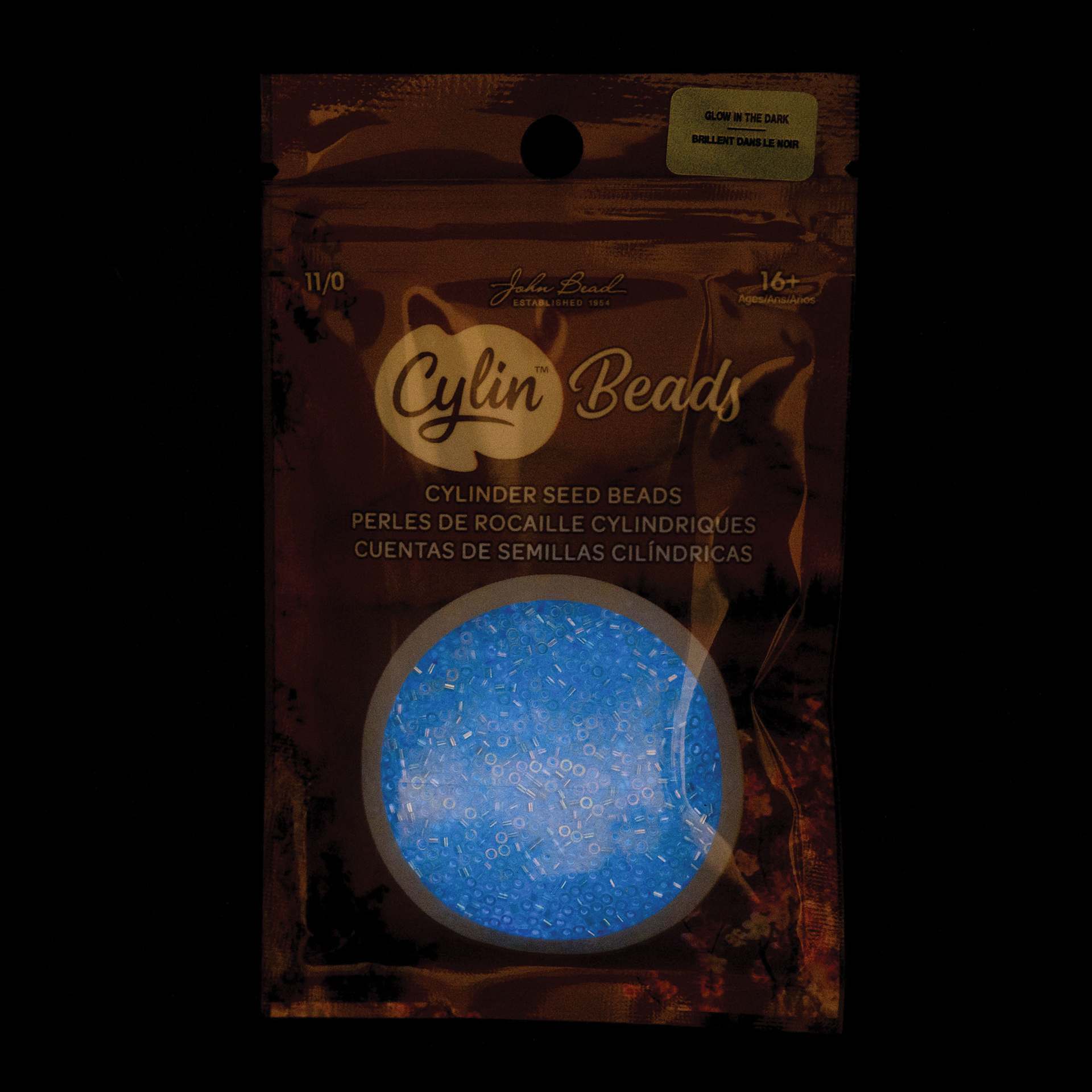 John Bead Cylin 11/0 Glow in the Dark Cylindrical Seed Beads - Sky AB, 25g front of packaging to show glow effect