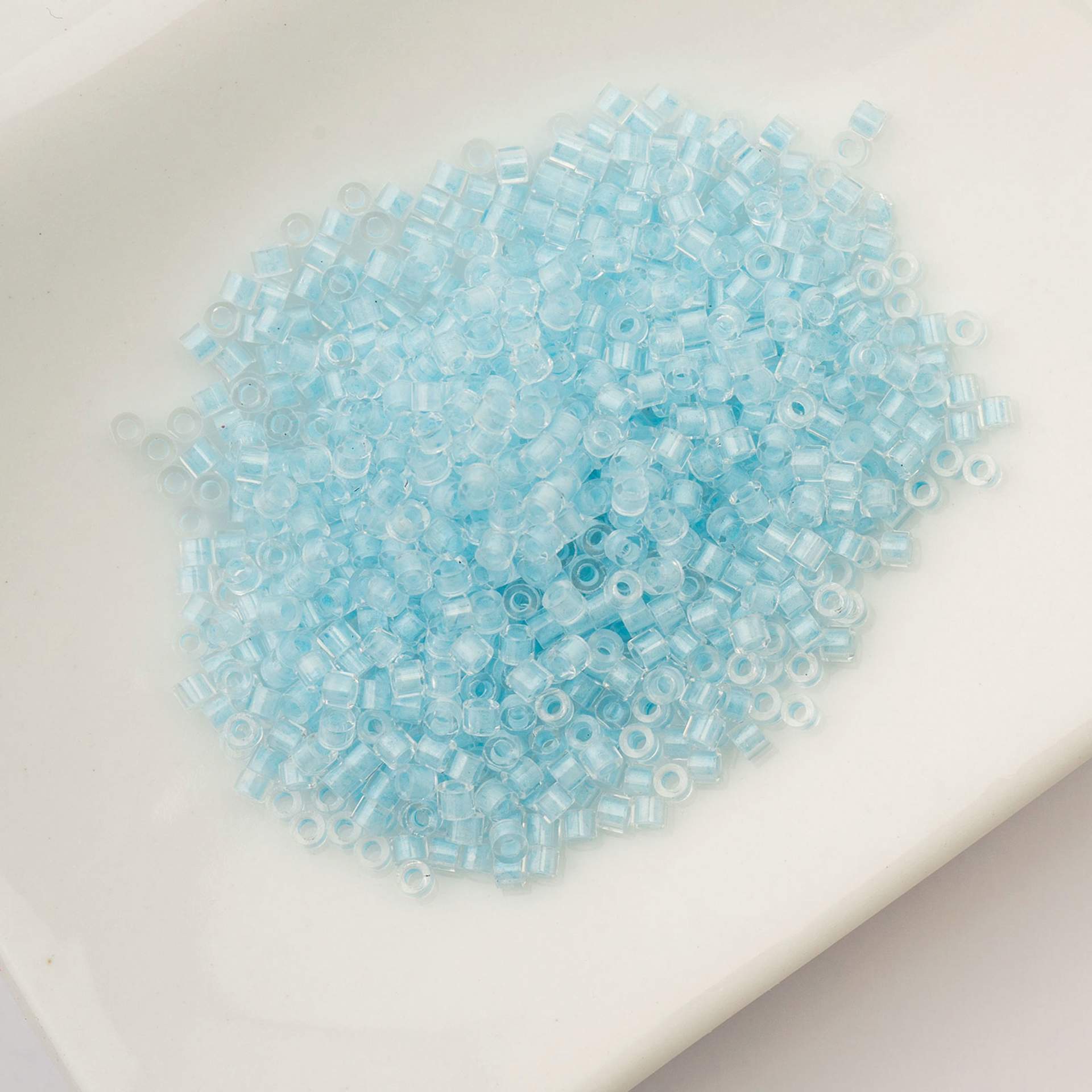 John Bead Cylin 11/0 Glow in the Dark Cylindrical Seed Beads - Sky, 25g sitting in dish