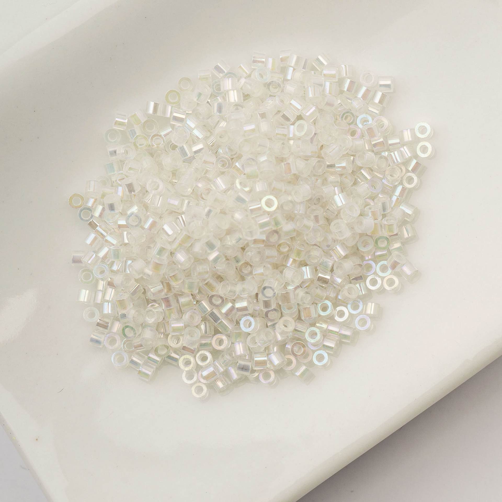 John Bead Cylin 11/0 Glow in the Dark Cylindrical Seed Beads - White to Sky AB, 25g sitting in dish