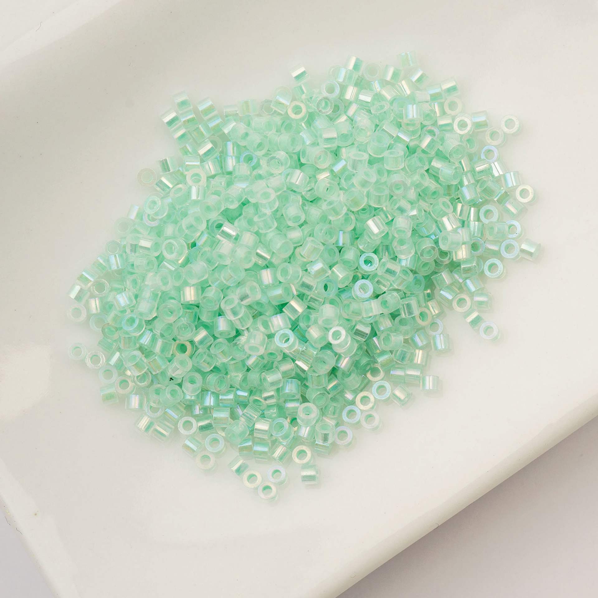 John Bead Cylin 11/0 Glow in the Dark Cylindrical Seed Beads - Green AB, 25g sitting in dish