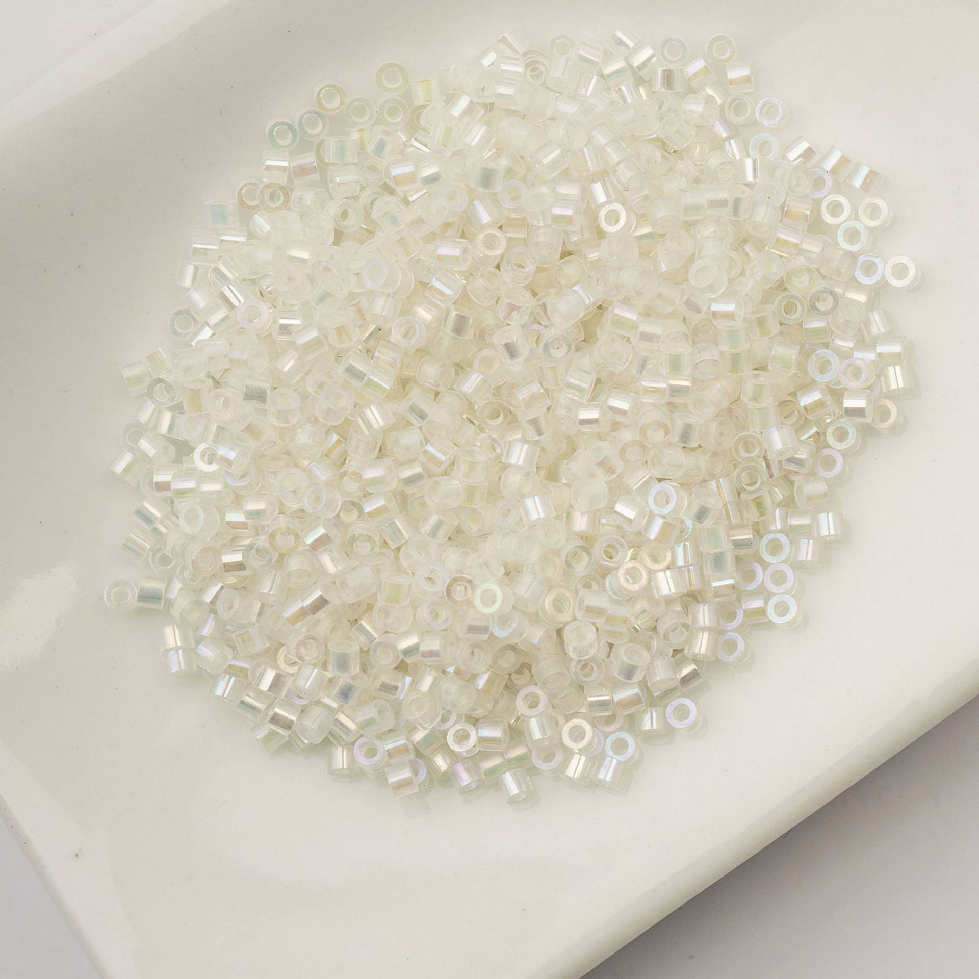 John Bead Cylin 11/0 Glow in the Dark Cylindrical Seed Beads - White to Green AB, 25g sitting in dish