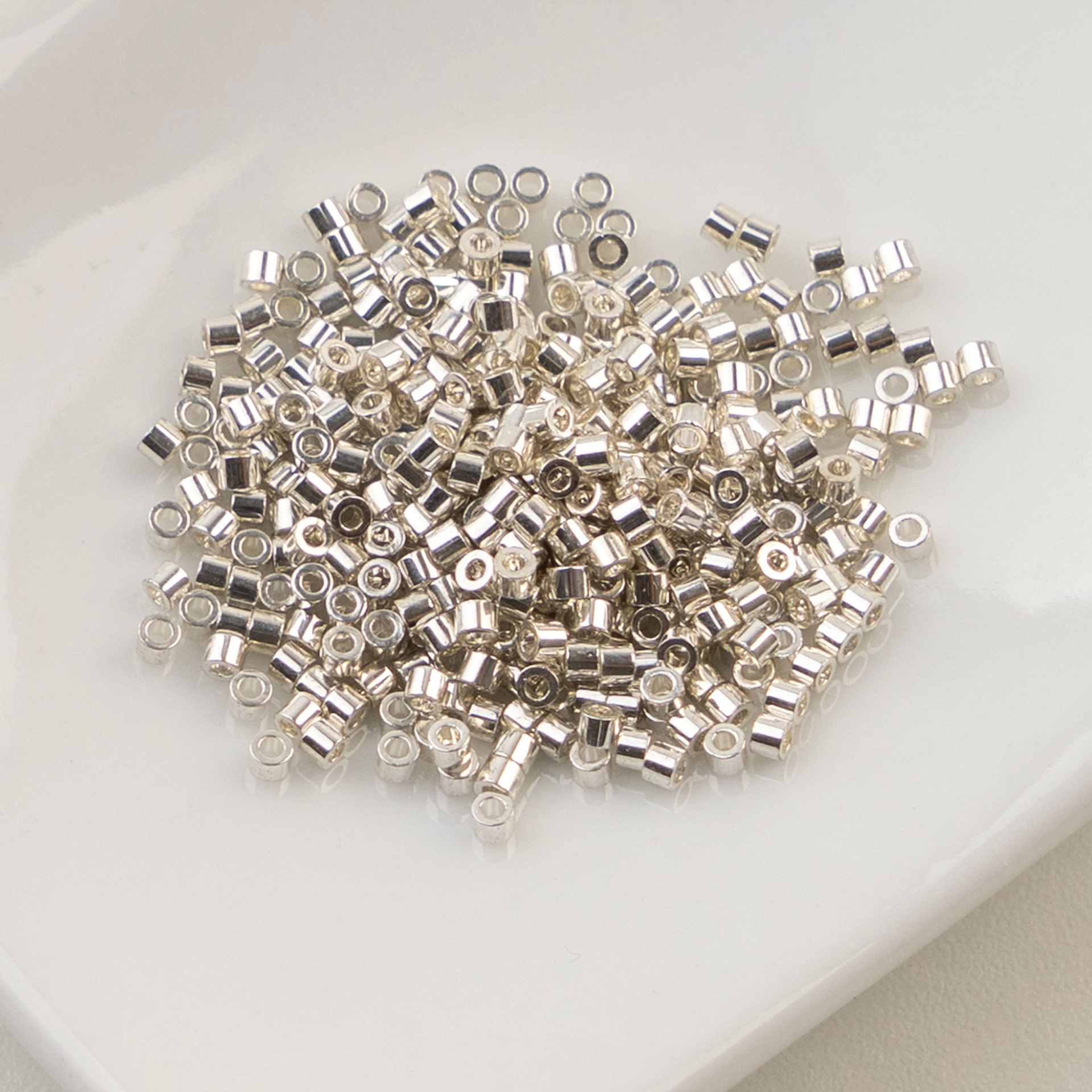 John Bead Cylin 11/0 Cylindrical Seed Beads - Electro Silver sitting in dish
