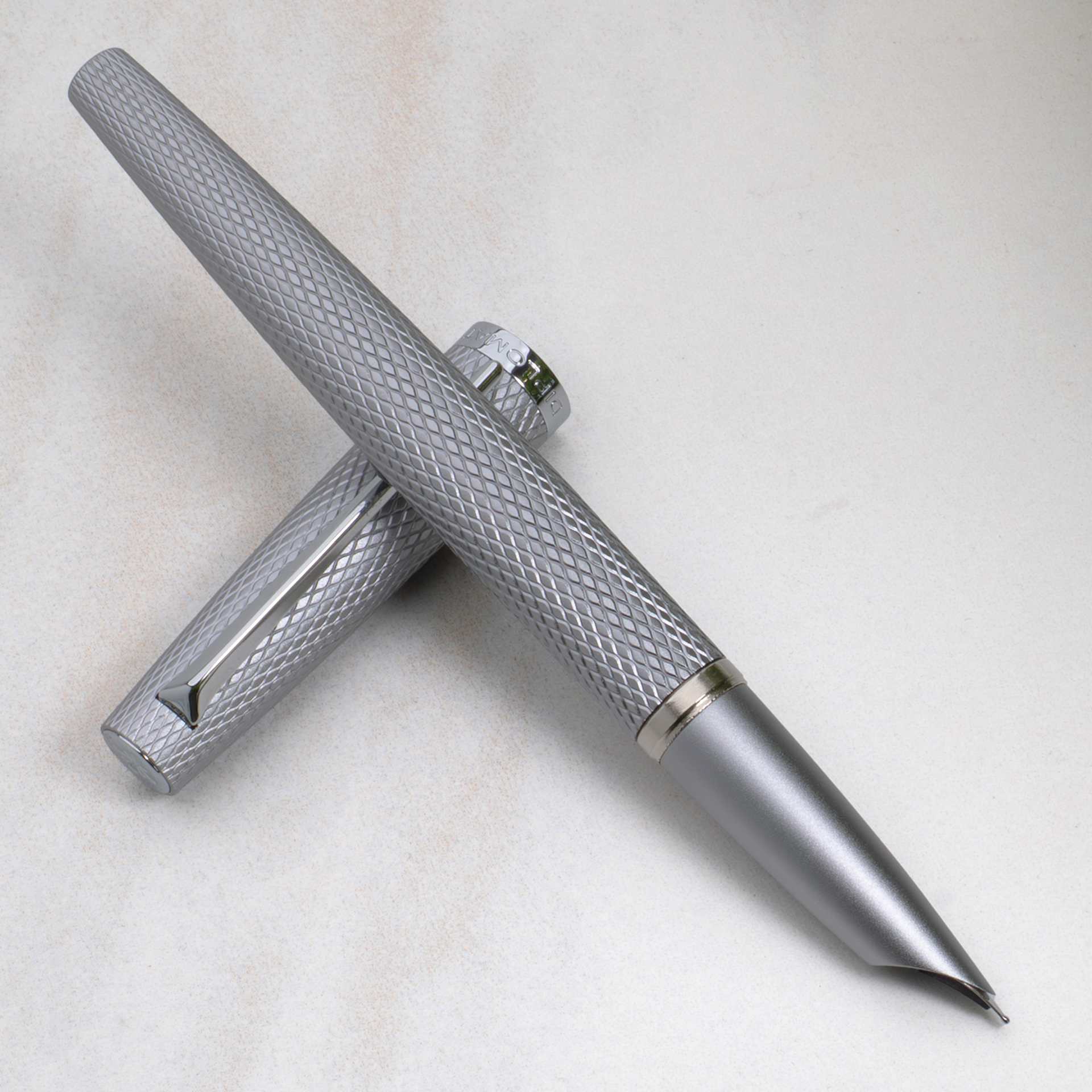 Diplomat Viper Fountain Pen - Silver Guilloche pen and cap resting on tabletop