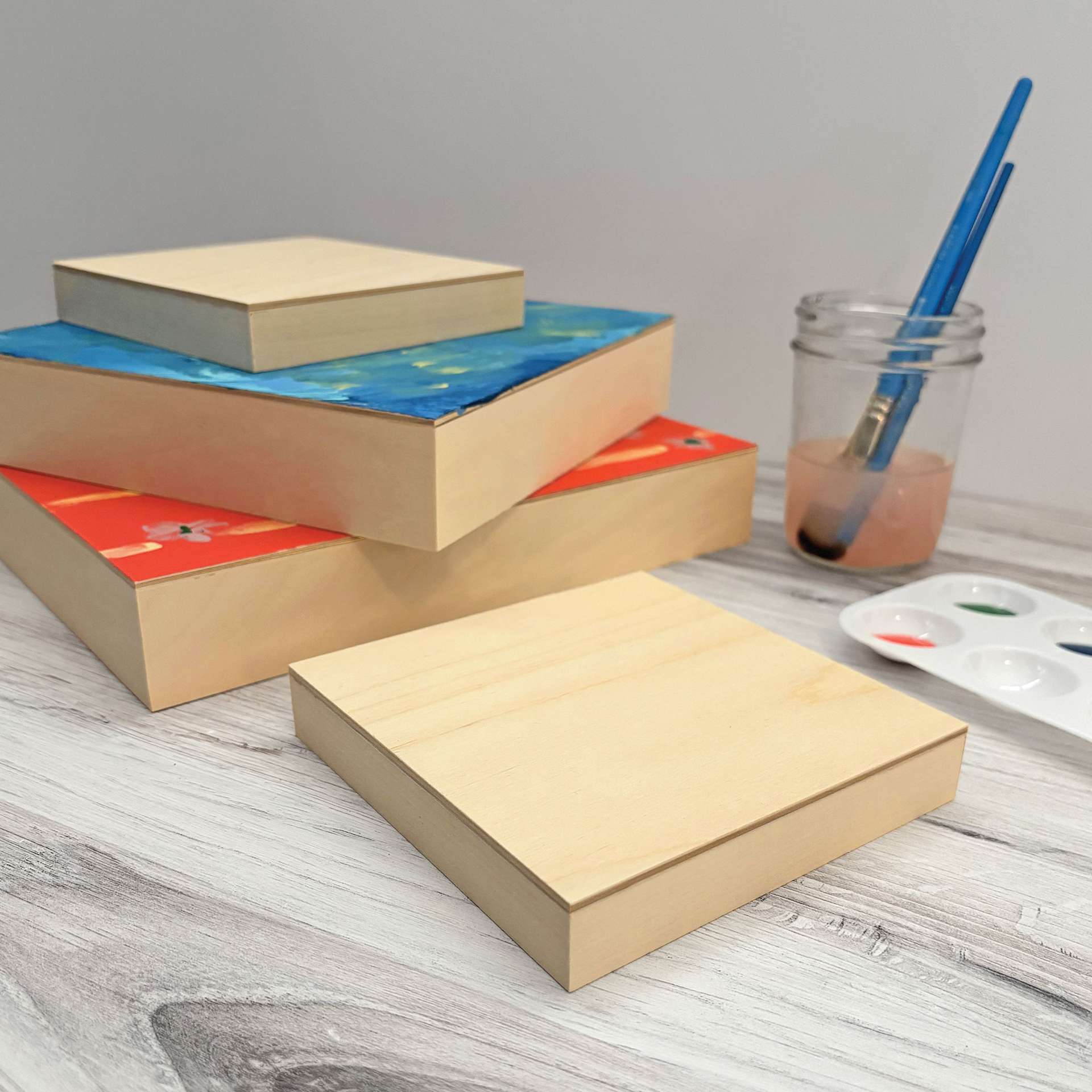 A stack of Ampersand Woodpanels on a table ready to be painted.