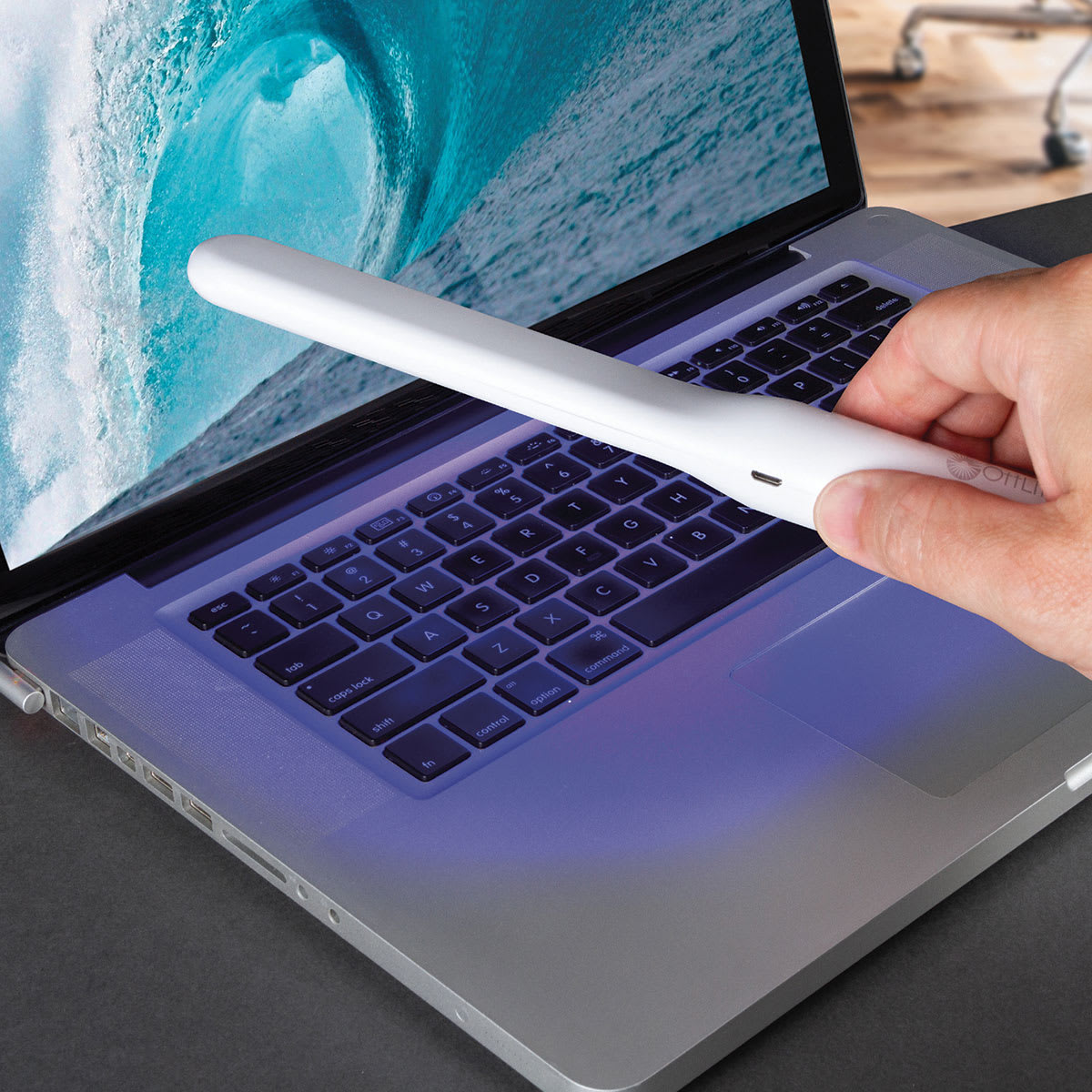 OttLite Rechargeable UVC Disinfecting Wand (Person using disinfecting wand to disinfect laptop)