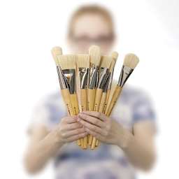 Blick Mega Natural Bristle Brushes - Model holding a fan of several brushes in front of her face
