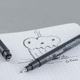 Pentel Arts Pointliner Pen - Uncapped Black pen with sketch of cupcake on graph paper