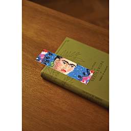 DMC The Masters Collection Cross Stitch Bookmark Kit - "The Frame" by Frida Kahlo ontop of book