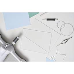Sizzix Cutting Pads - Accessory A5, 6-1/8" x 10-1/4" x 1/8" laying on table with other tools (only single cutting board included)