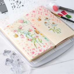 Sizzix Studio Registration Press Tool Starter Kit showing completed floral design project in notebook