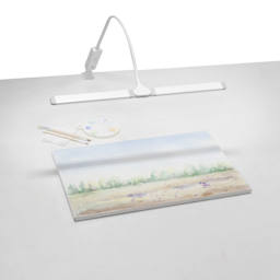 Artograph Split Bar Lamp with Table Clamp - White, on a desk with artwork