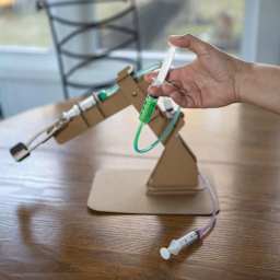 Kikkerland Newton’s Lab Make Your Own Hydraulic Claw Kit (Person pushing syringe to start hydraulic claw)