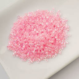 John Bead Cylin 11/0 Glow in the Dark Cylindrical Seed Beads - Pink AB, 25g sitting in dish