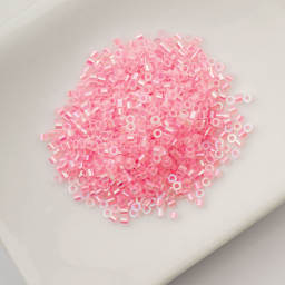 John Bead Cylin 11/0 Glow in the Dark Cylindrical Seed Beads - Rose AB, 25g sitting in dish
