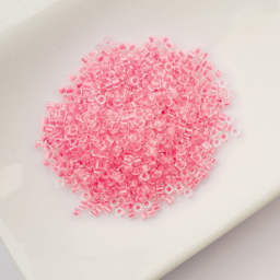John Bead Cylin 11/0 Glow in the Dark Cylindrical Seed Beads - Rose, 25g sitting in dish